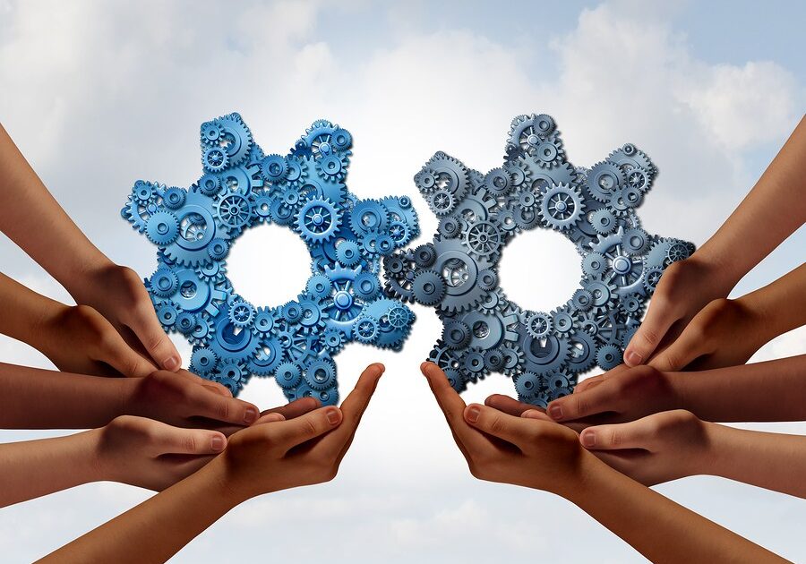 imagen-de-emprendimiento-colaboracion Corporate teamwork and business global cooperation concept as two groups of diverse people joining together holding a giant gear made of smaller gears and cog wheels with 3D illustration elements.